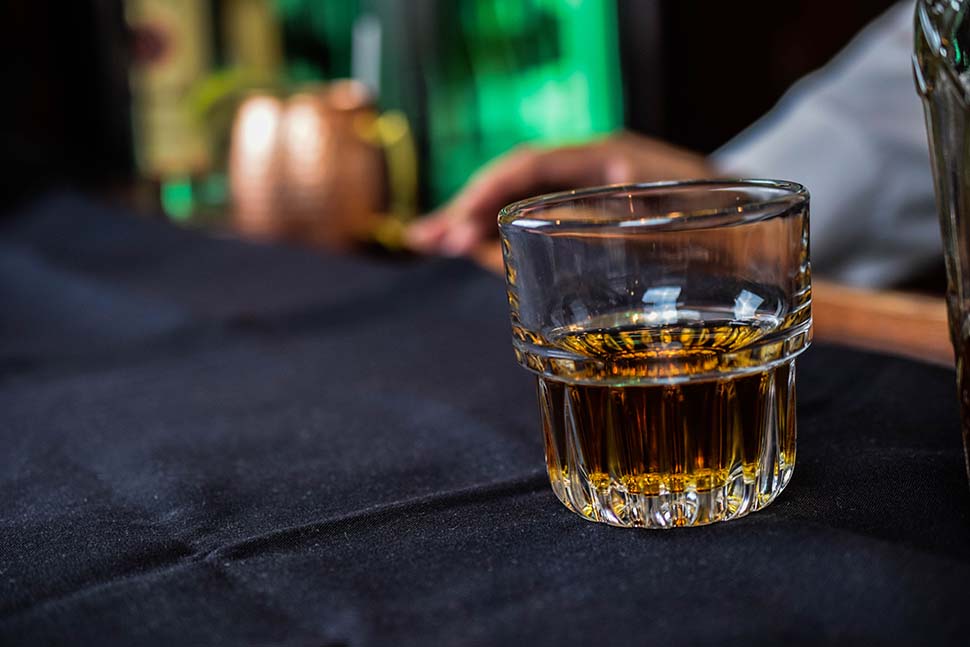 A close-up of a glass of whiskey on a black tablecloth.