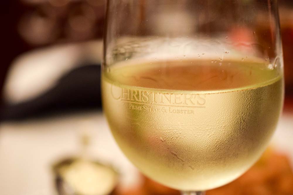 a glass of Christner's white wine on a table