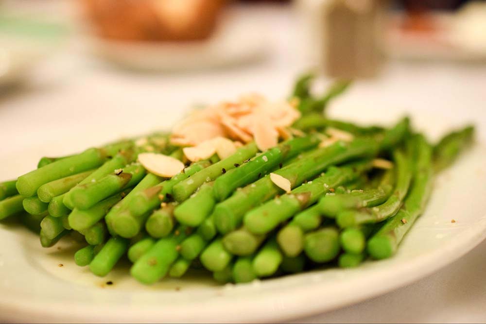 asparagus with nuts and seasoning on a white plate