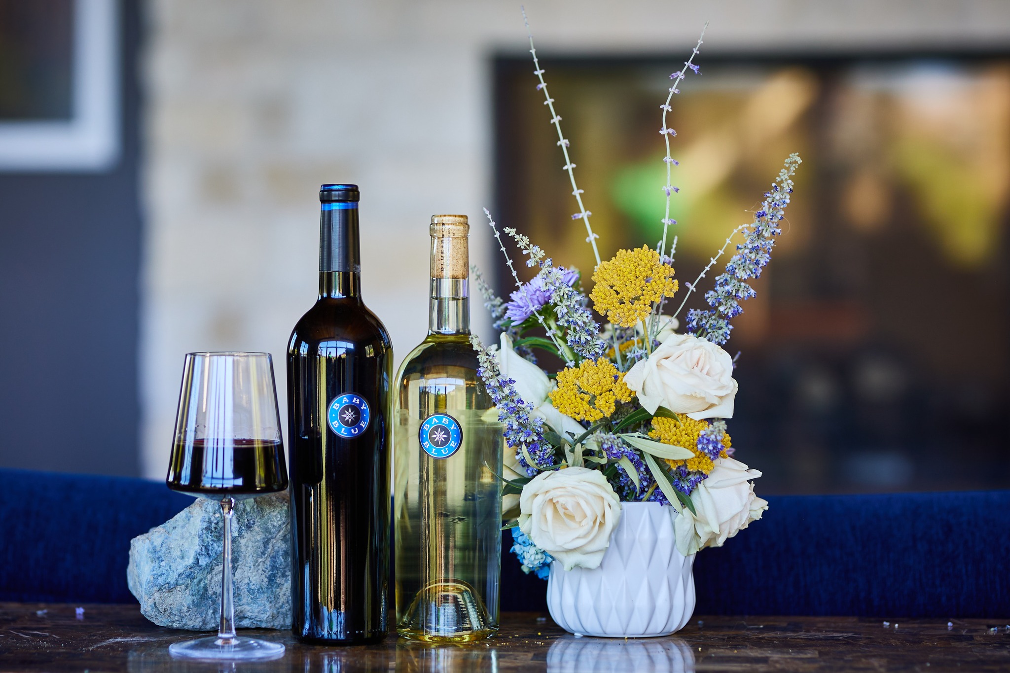 Blue Rock Winery wines on a table next to flowers and a glass of wine