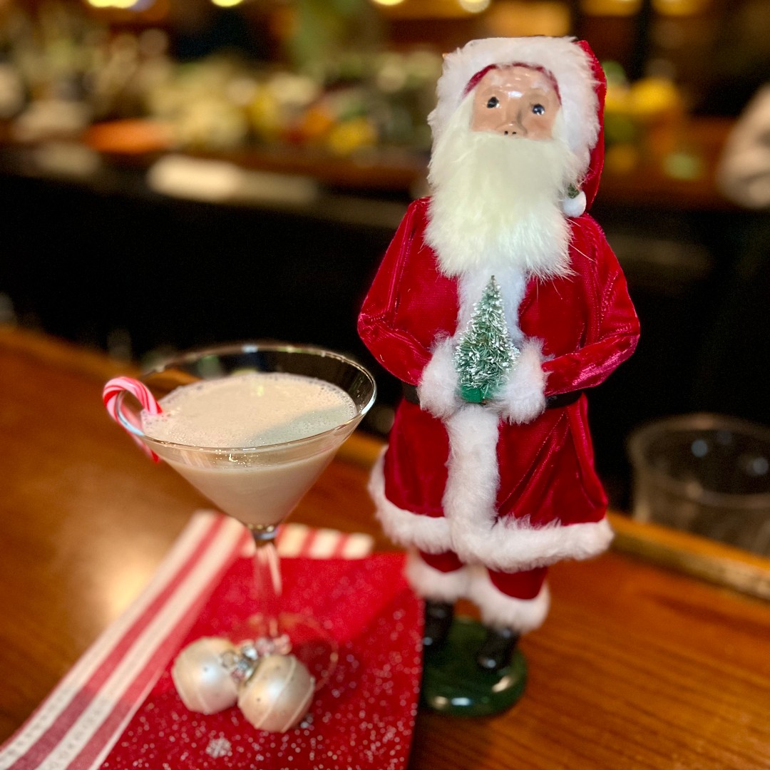 Russ' Christmas Kiss cocktail with a candycane on a white tablecloth